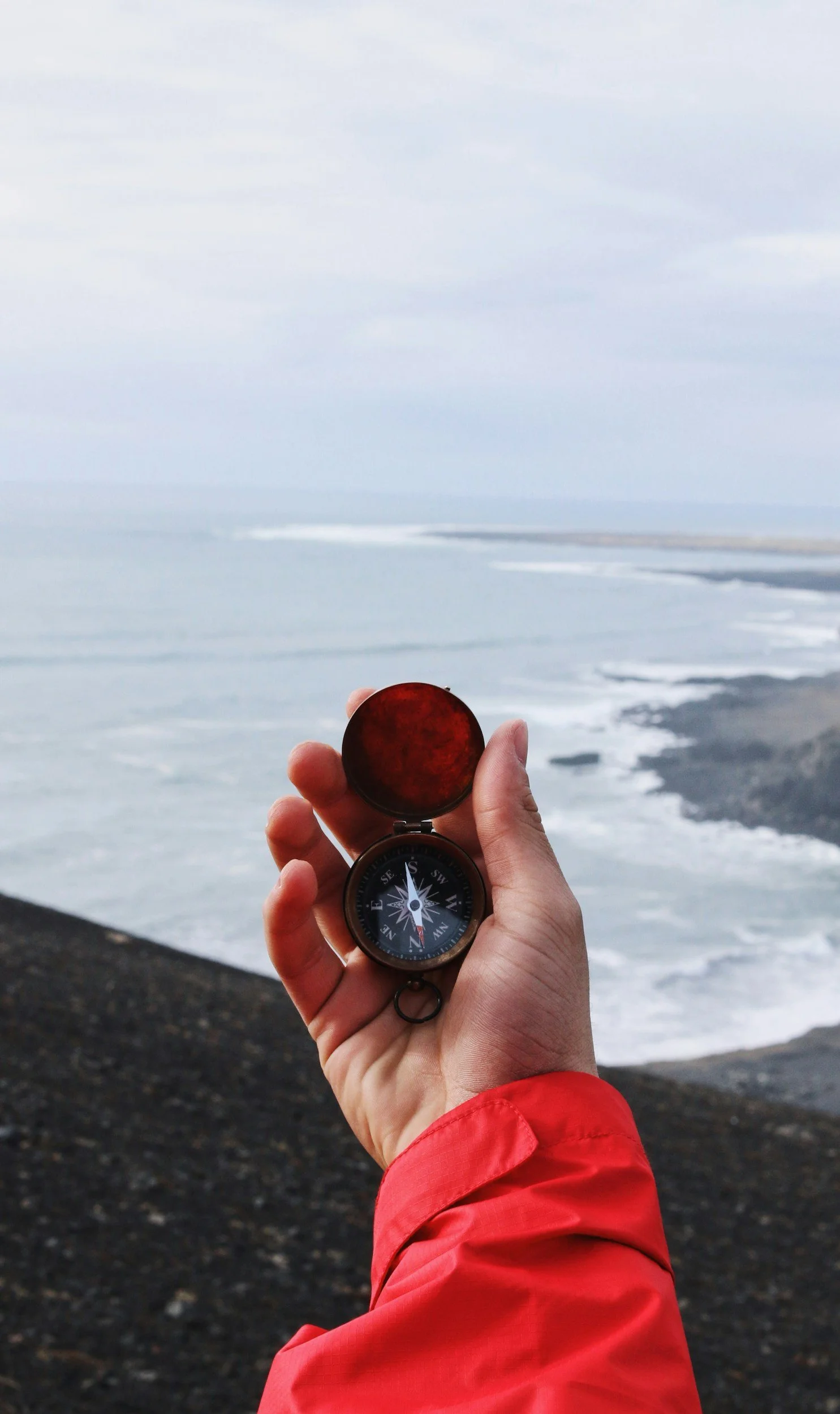 Person holding a compass, overlooking the ocean
