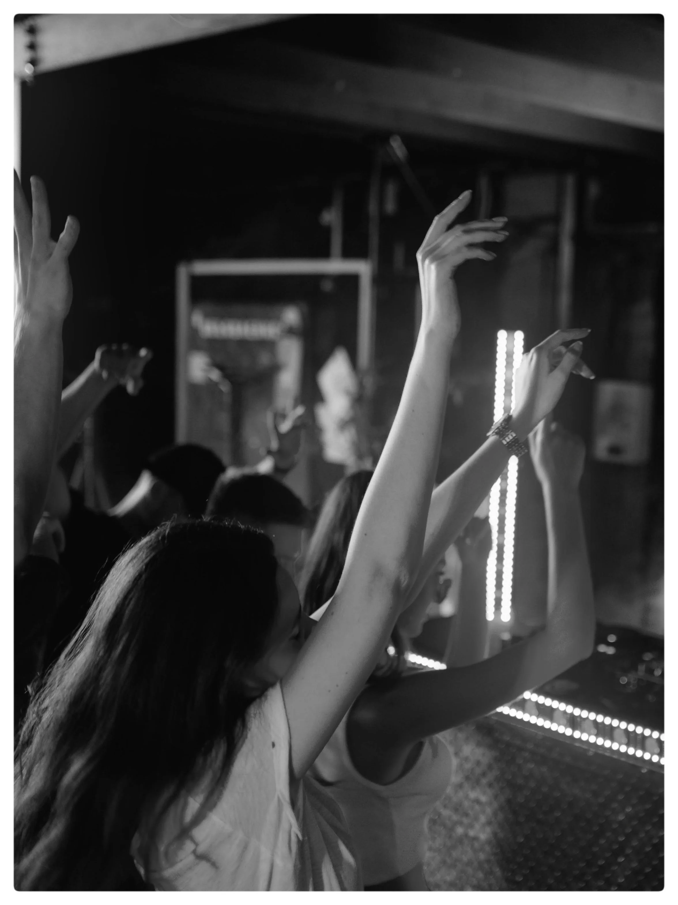 A group of people with raised hands in a concert or event setting, black and white photo.