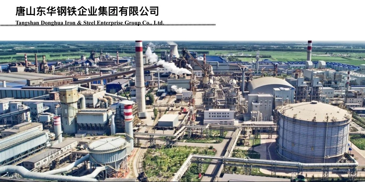 An aerial view of a large industrial factory complex with multiple chimneys emitting steam and smoke, storage tanks, and interconnected pipelines.