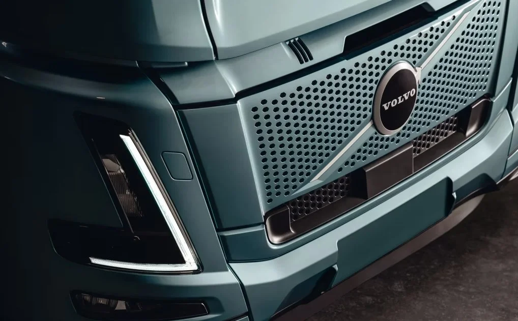 Close-up of the front grille and headlight of a Volvo truck showing the brand logo.