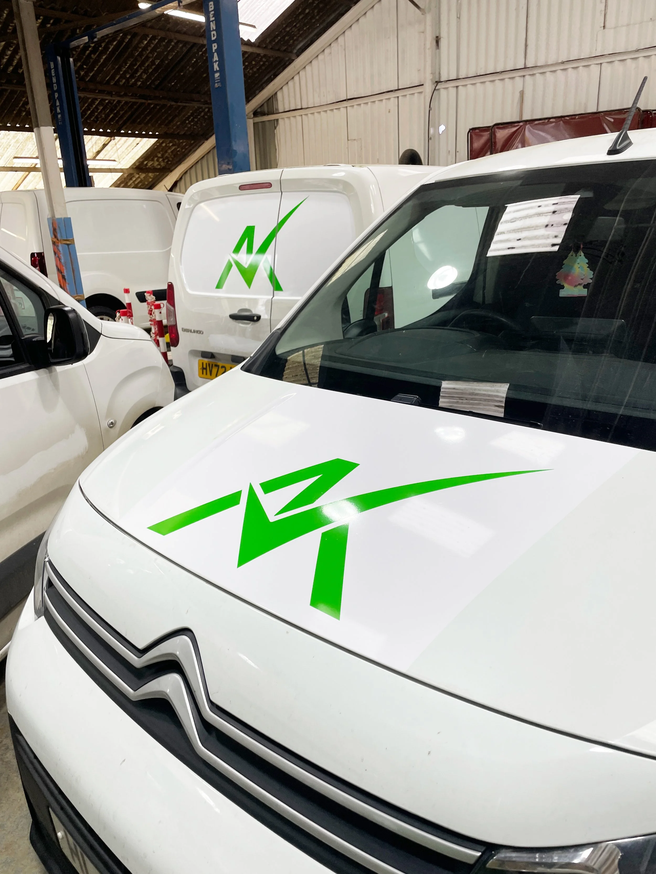 White vans with green logo decals inside a garage or warehouse.