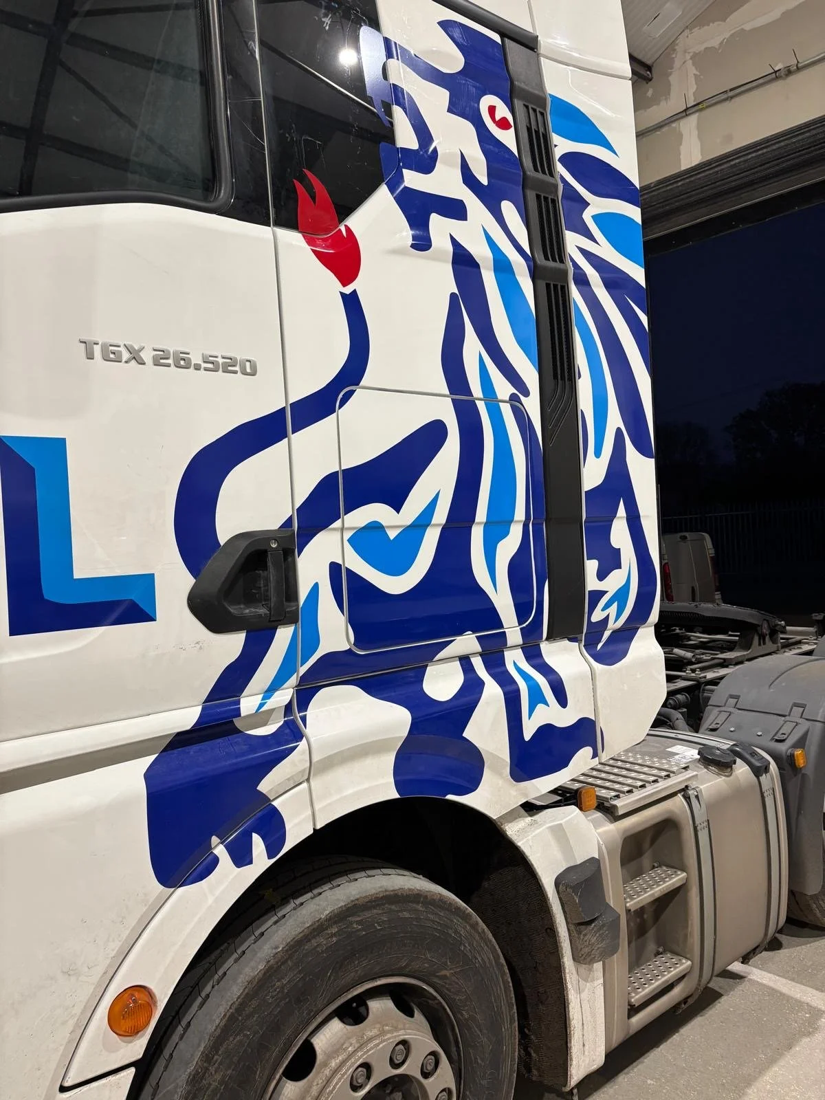 Close-up of a semi-truck with a blue and white lion mural on its side.