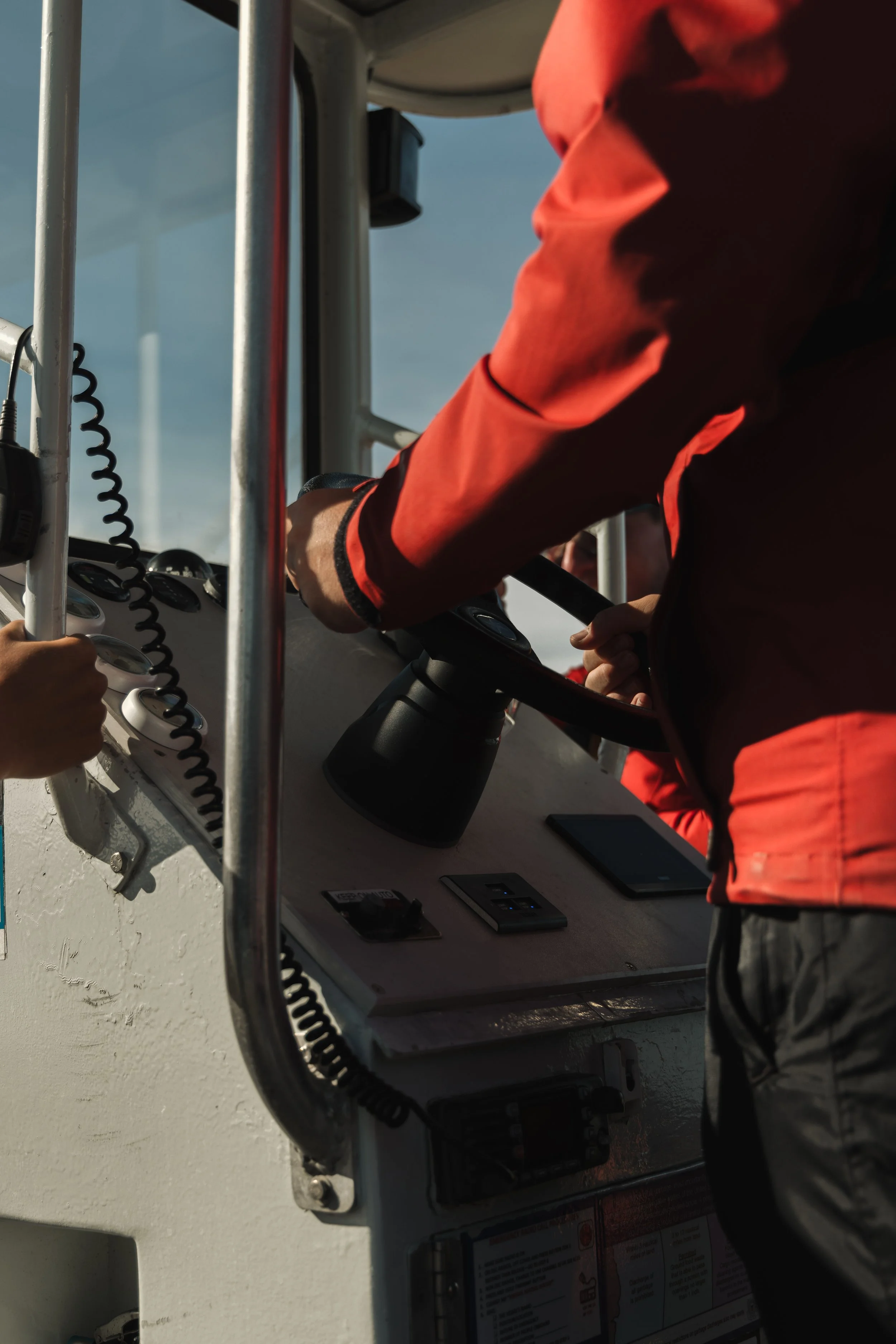 A person operating an industrial control panel with switches and buttons, in an outdoor setting with a bright sky.