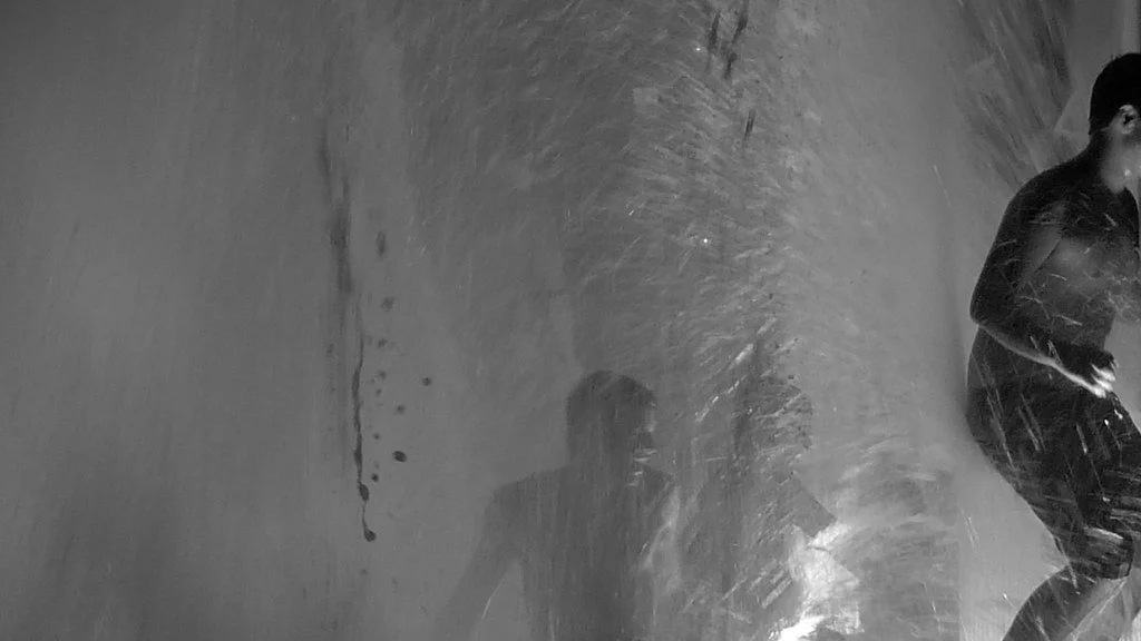 People playing in the rain with a textured wall in the background.