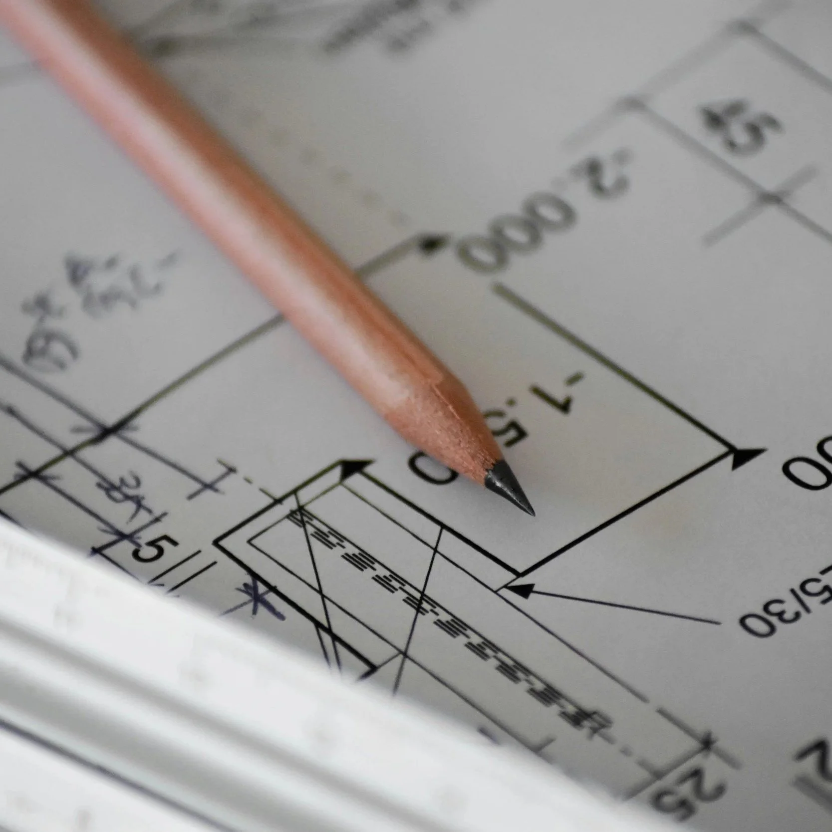 Un crayon posé sur un plan technique ou dessin d'ingénierie.