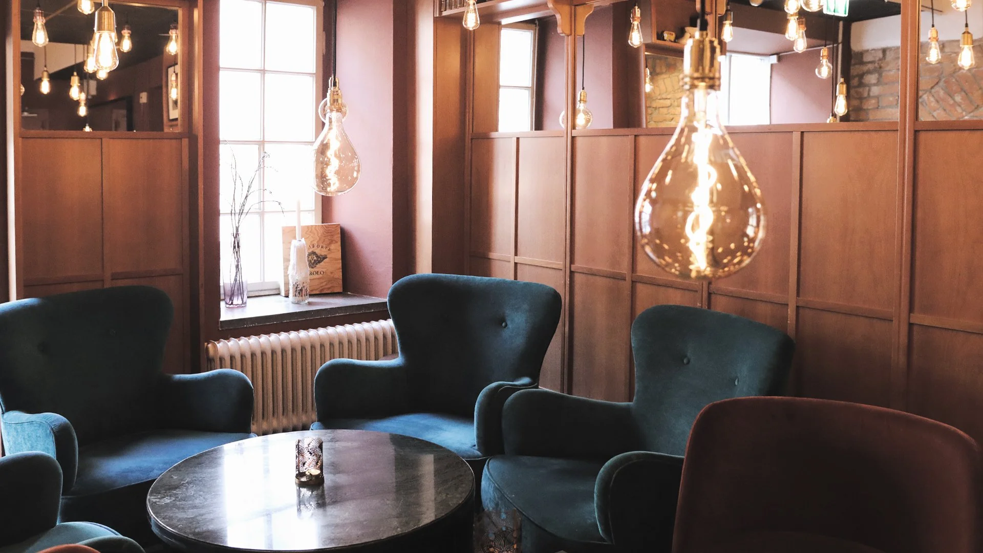 NOFO - Loungeyta, stolar i sammet, pendellampor från tak.jpg