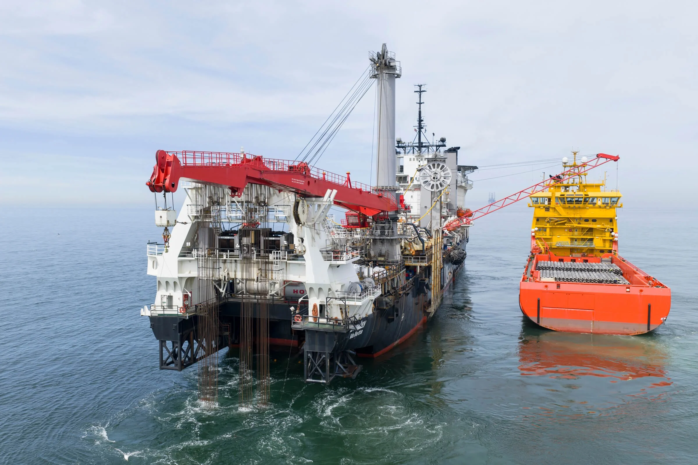 An oil drilling ship at sea with a supply boat nearby.