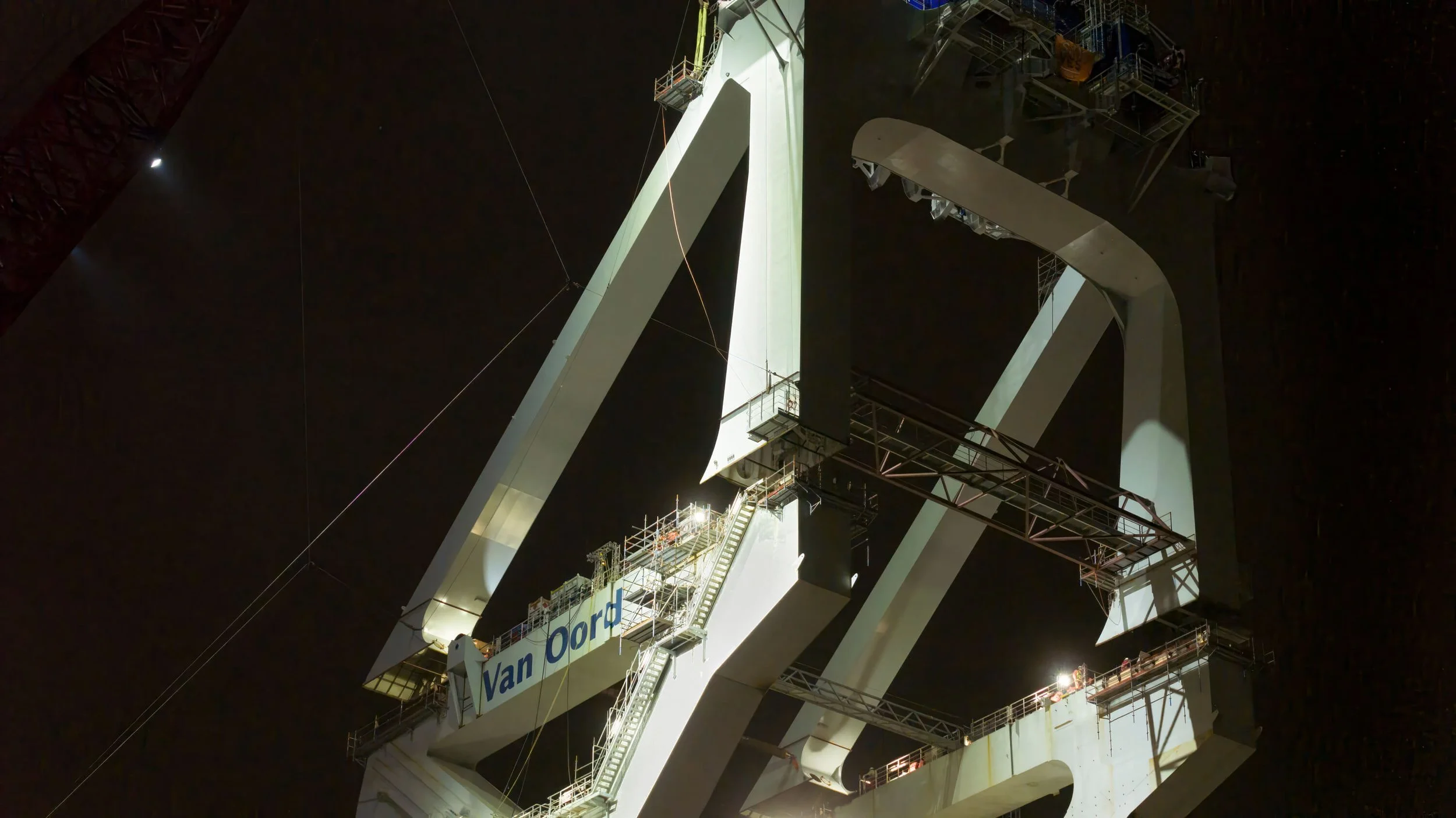 Close-up of the massive structure of the Van Oord Crane at night, with lights illuminating parts of the heavy machinery.