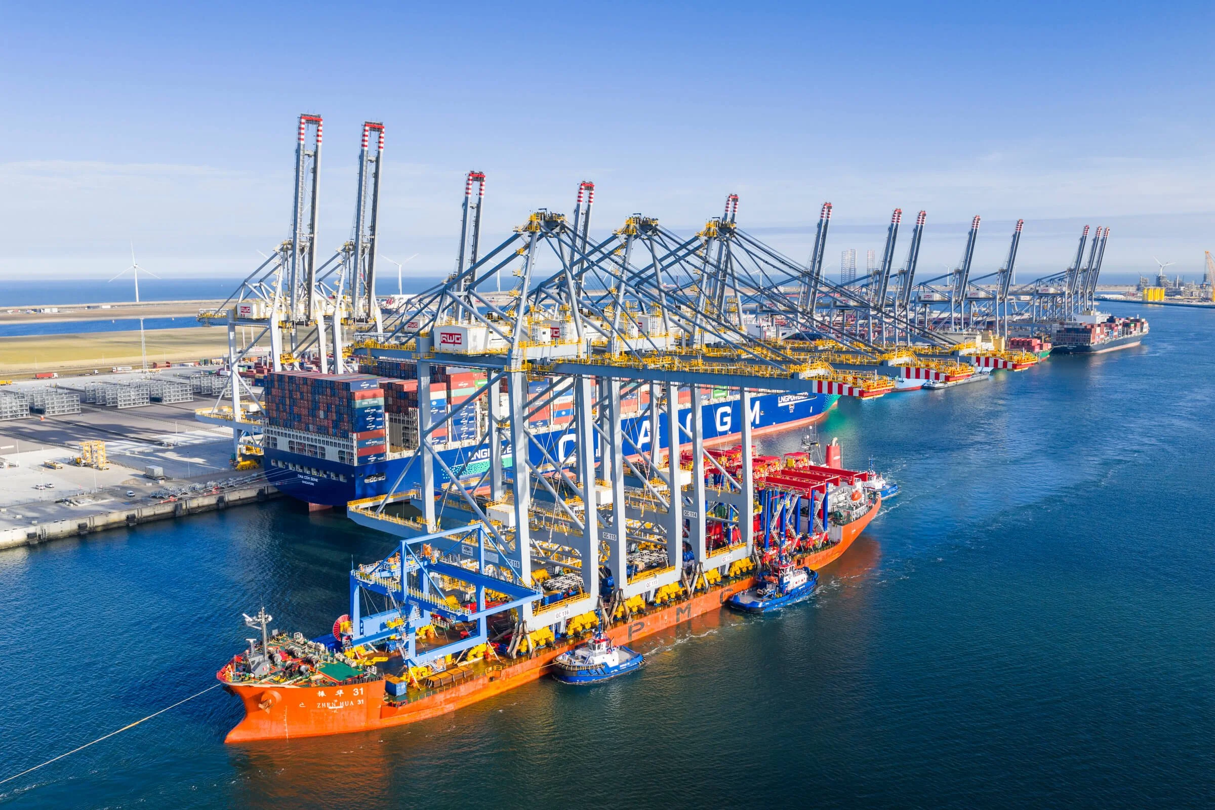 Large container ship docked at a port with numerous cargo cranes for loading and unloading containers.