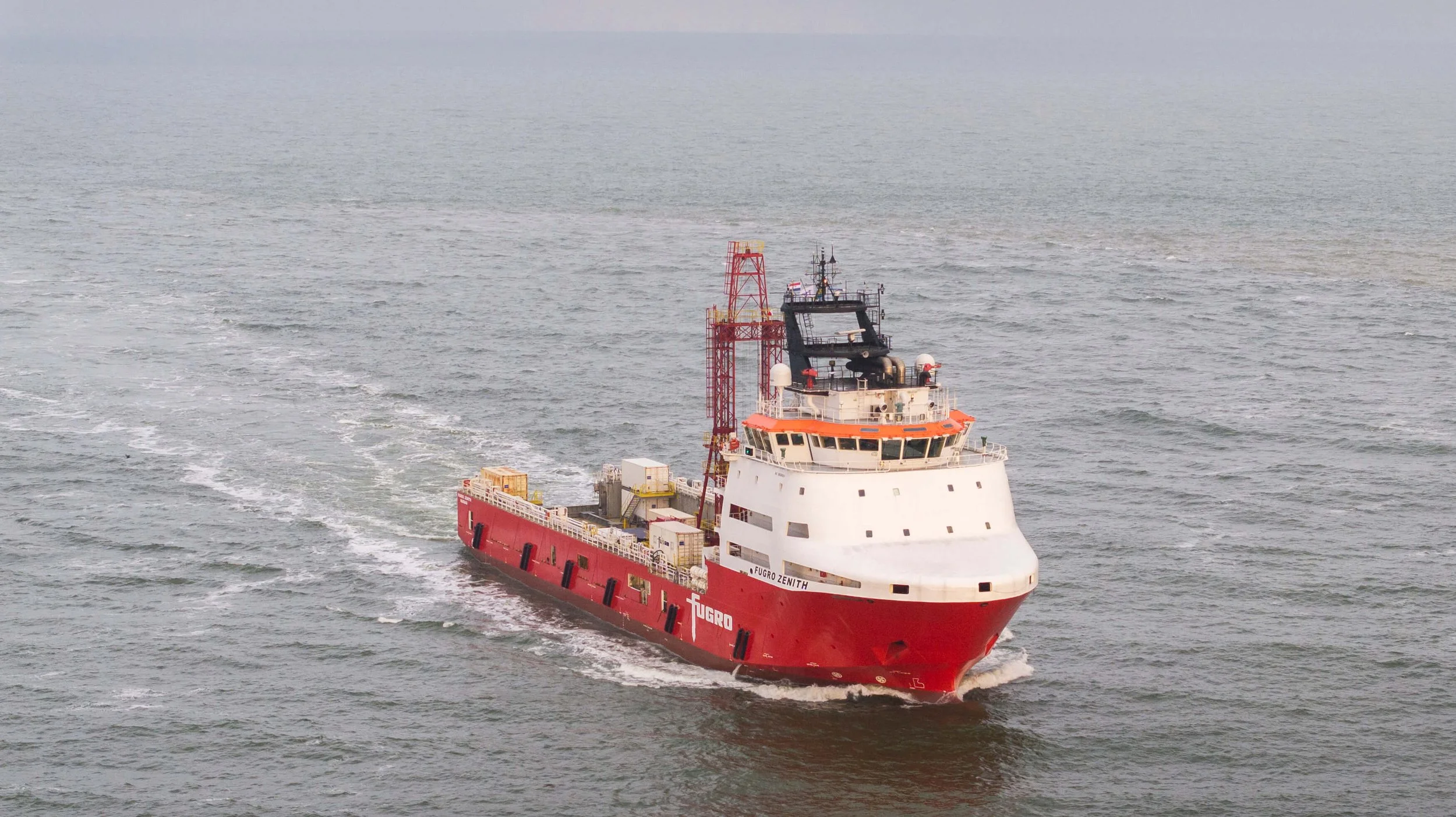 A large red and white ship named Fugro Zenith sailing through open water.