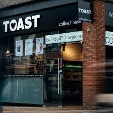 Exterior of Toast coffee house with signs on the window promoting local support and the hashtag #loveattoast.