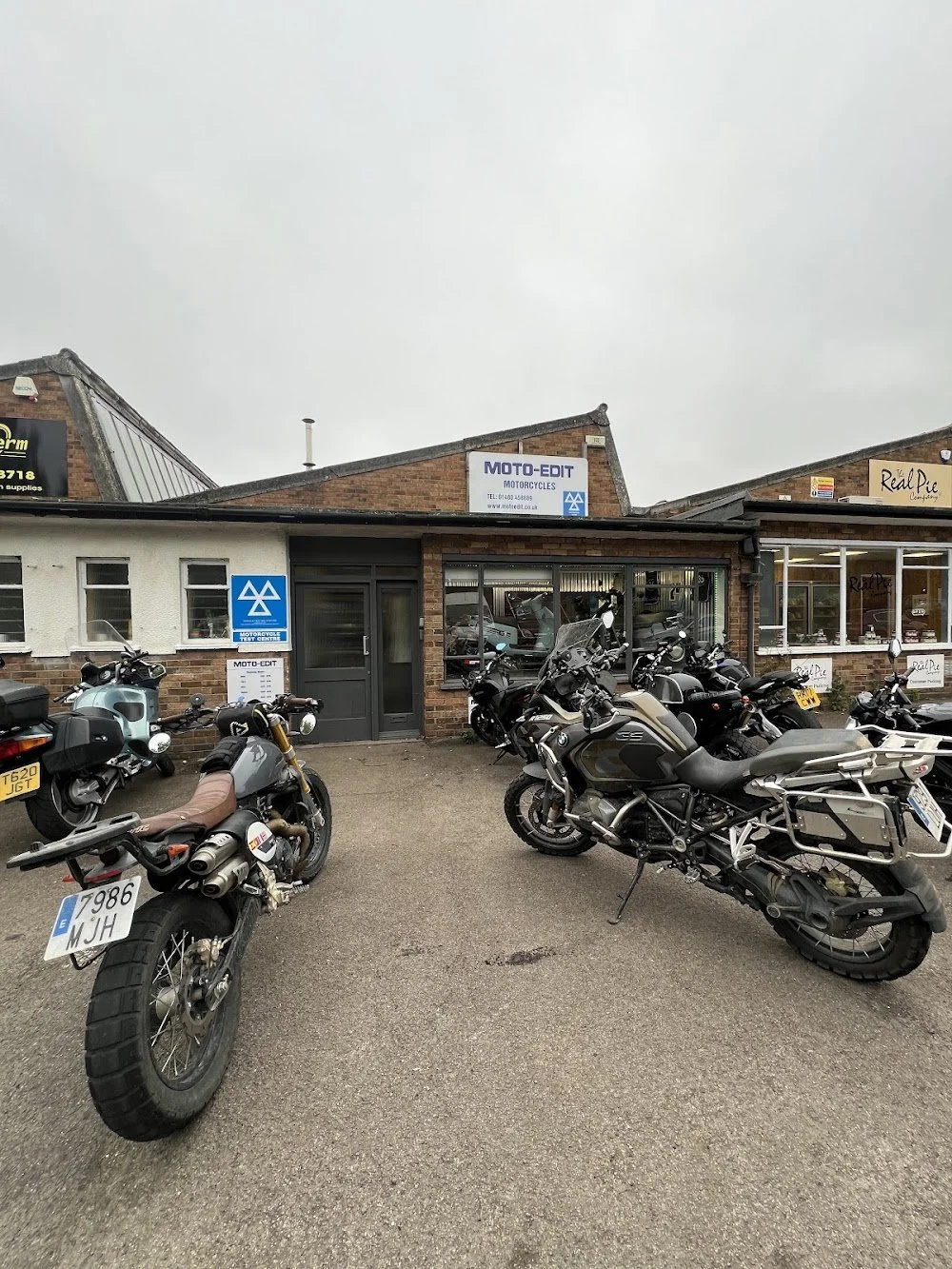 Motorcycle shop with multiple motorcycles parked outside, sign reads 'MOTO-EDIT MOTORCYCLES'