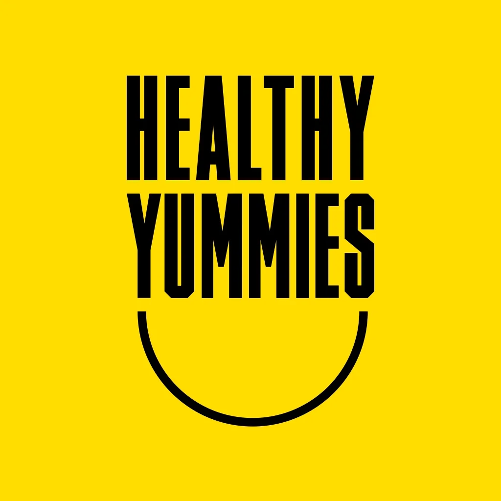 Yellow background with bold black text reading 'Healthy Yummies' and a partial black outline of a smiling face below the text.