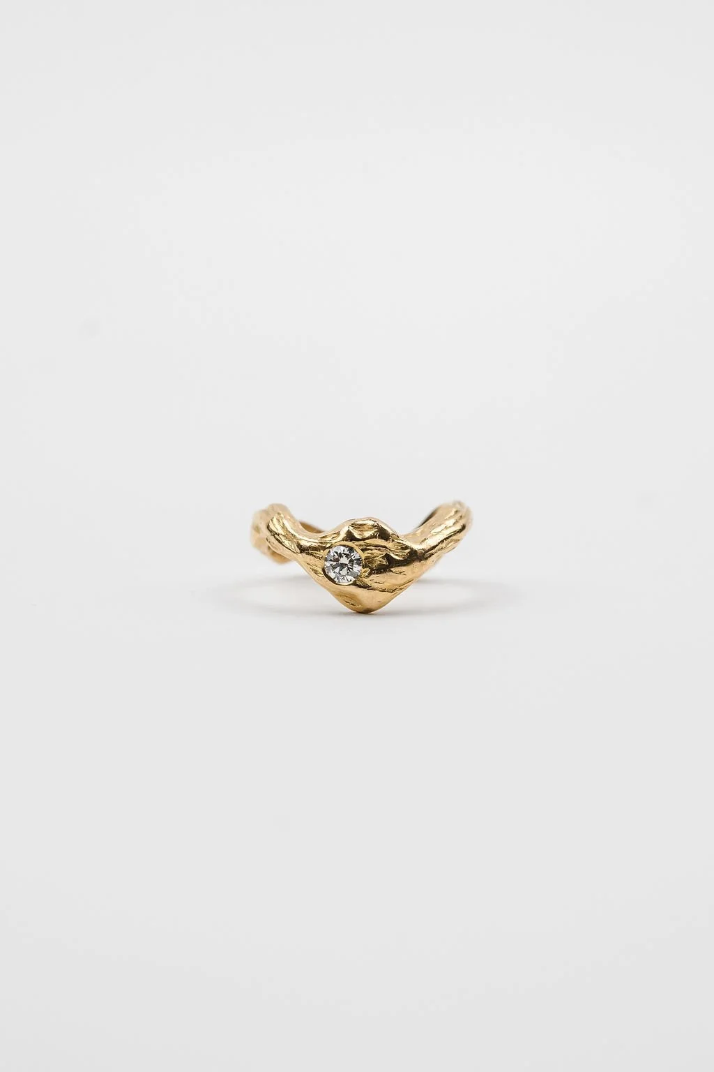 Gold ring with a textured surface and a small gemstone set in it, photographed against a plain white background.