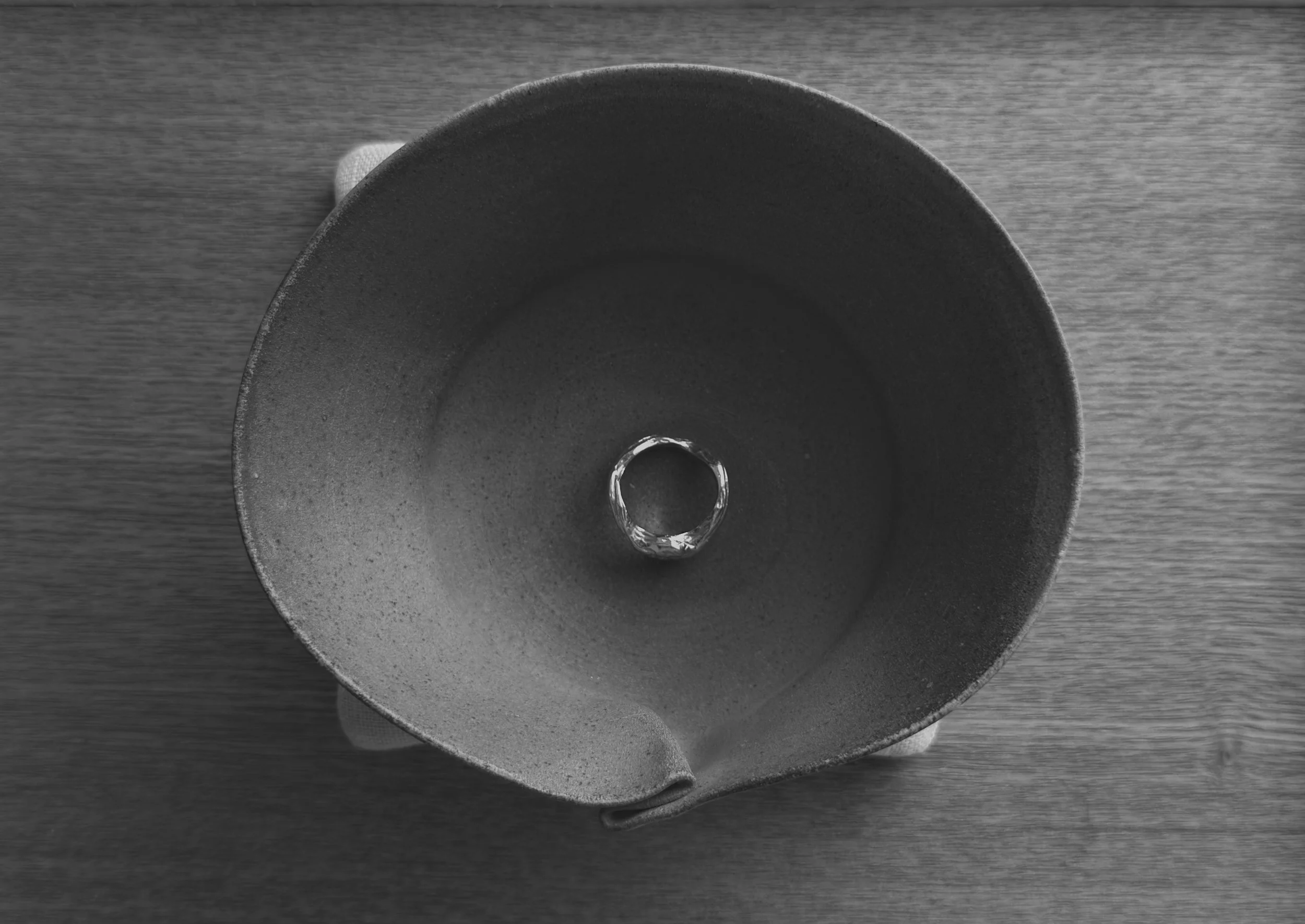 Top-down view of a black funnel with a ring inside, placed on a wooden surface.