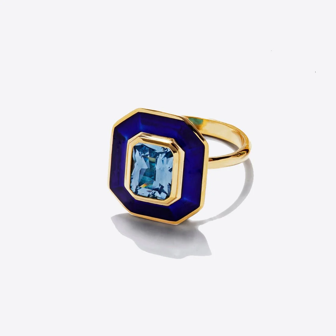 Gold ring with a rectangular light blue gemstone surrounded by a dark blue border, on a white background.