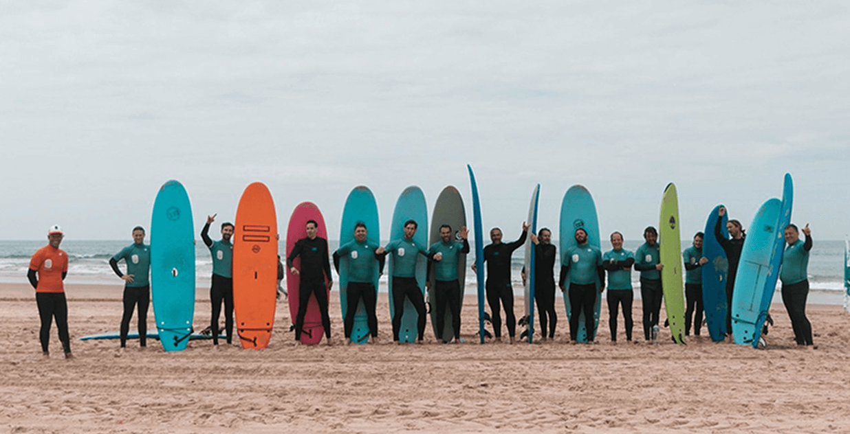 Group of people standing on a beach, holding colorful surfboards.