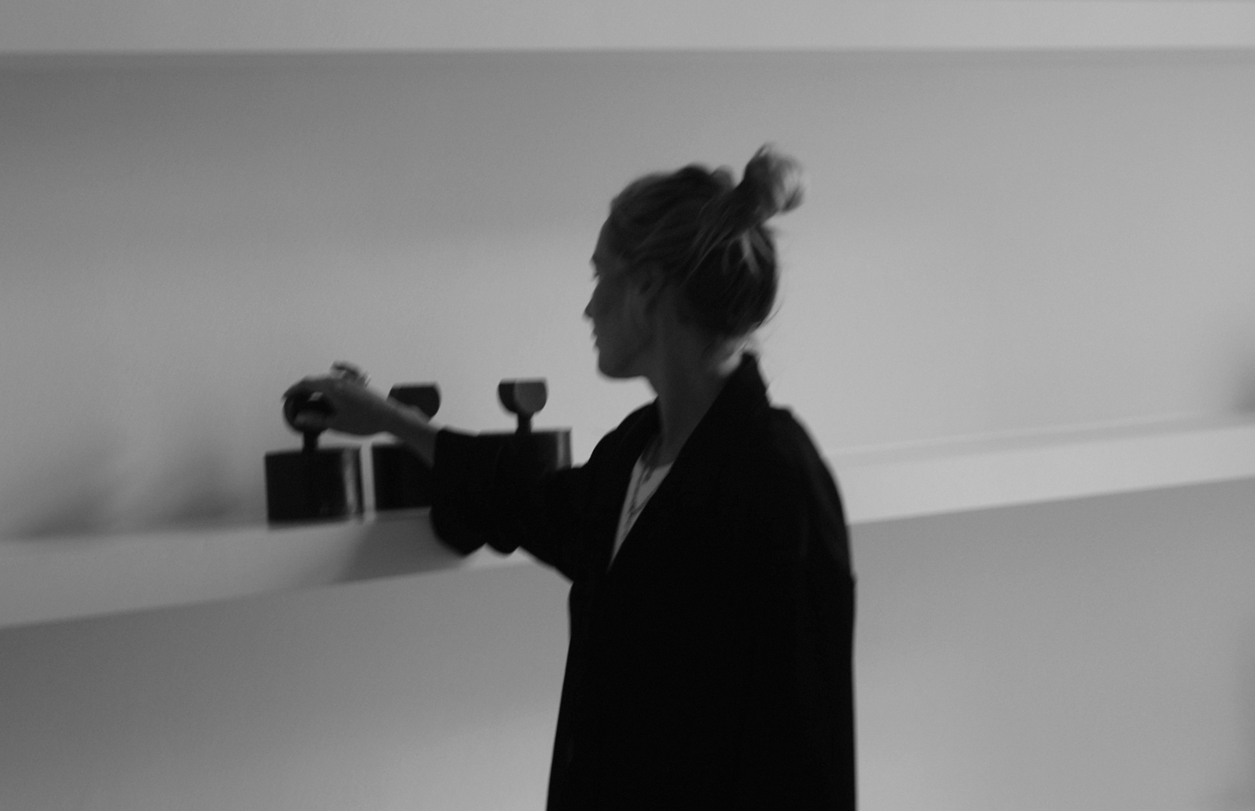 Schwarz-weiß-Foto einer Frau mit unordentlichem Haar, die eine Wandlampe bezieht.