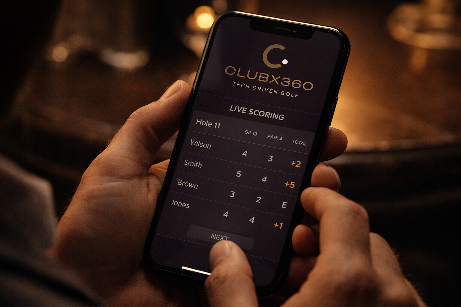 Person holding a smartphone displaying live golf scoring on the CLUBX360 app.