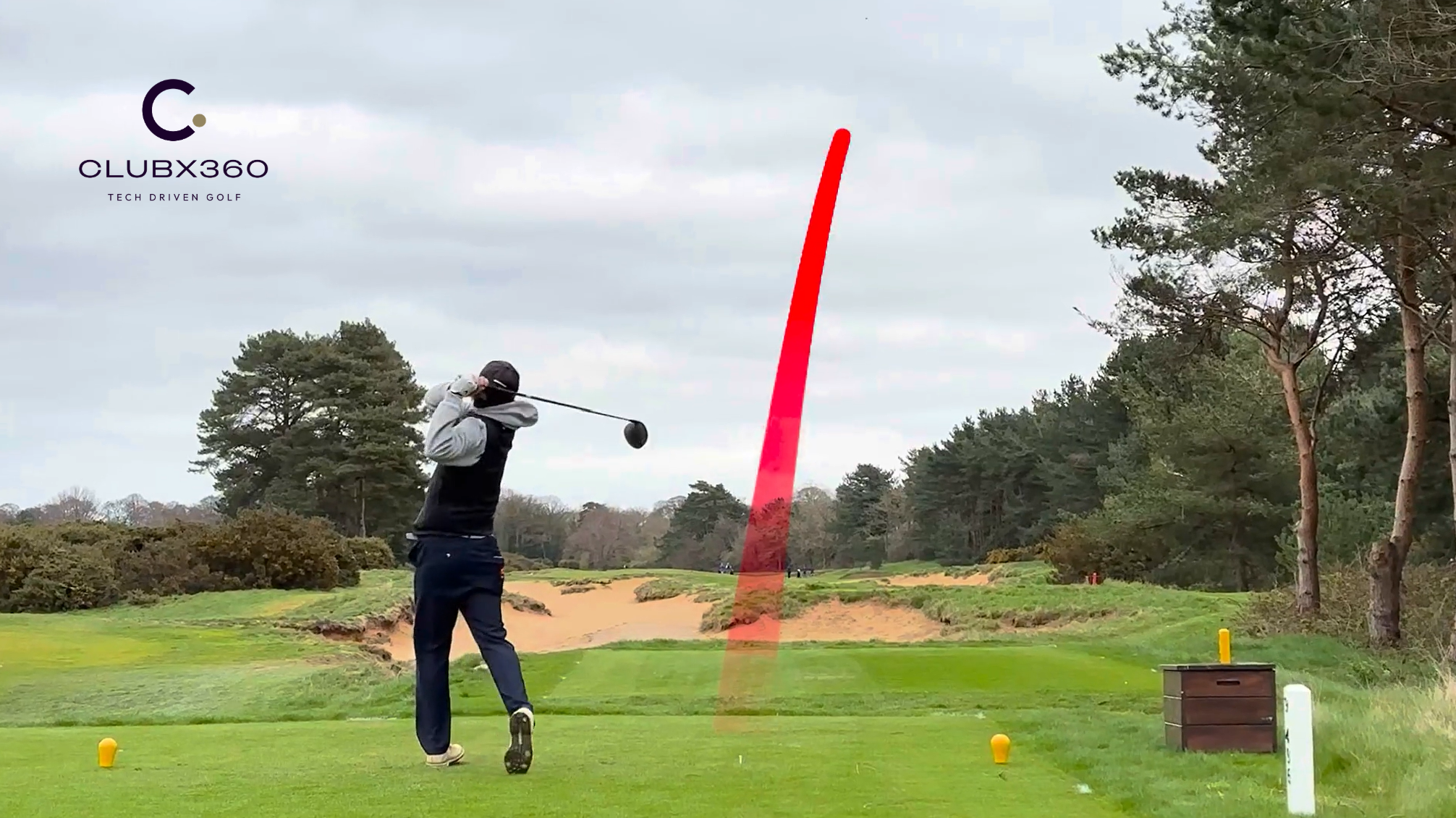 A person playing golf on a golf course, swinging a club, with trees and a cloudy sky in the background, and a red travel line indicating the ball's flight path.