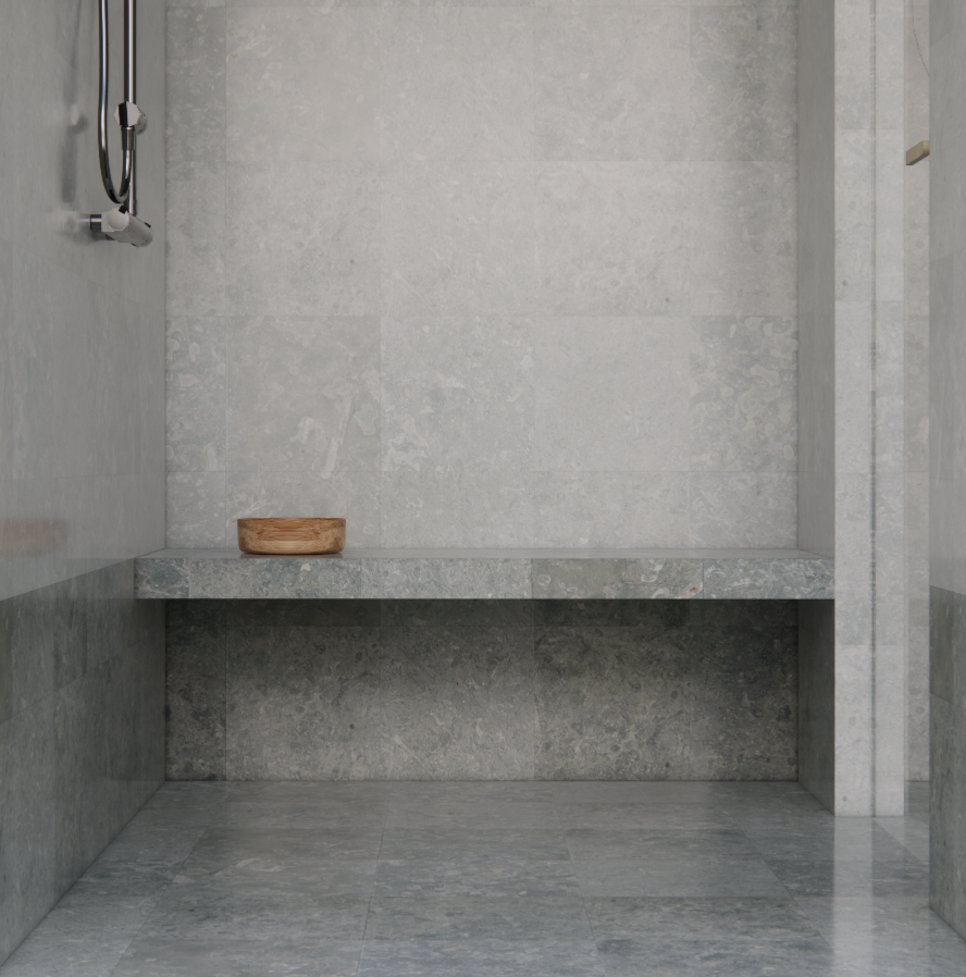 A minimalist shower space with gray stone walls and floor, a wall-mounted showerhead, and a wooden bowl on a built-in bench.