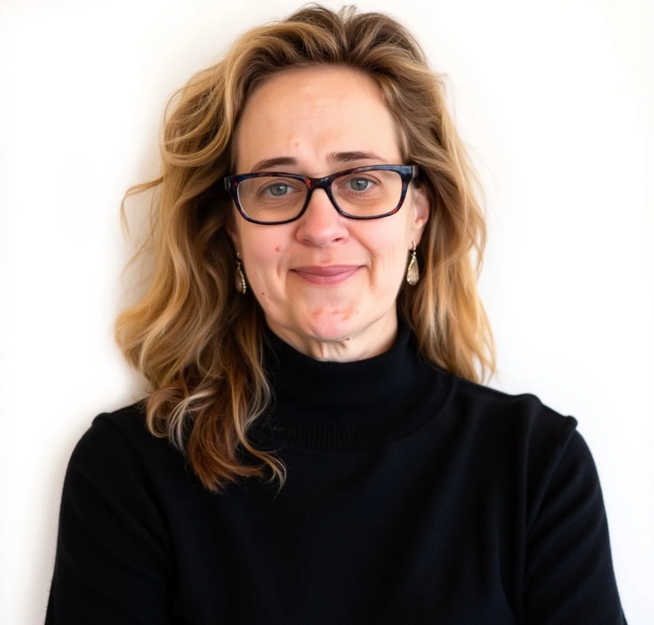 A woman with wavy light brown hair, wearing glasses, and black turtleneck.  Dr. Kelly Dickinson Pathwise Psychology Seattle and Tacoma, WA