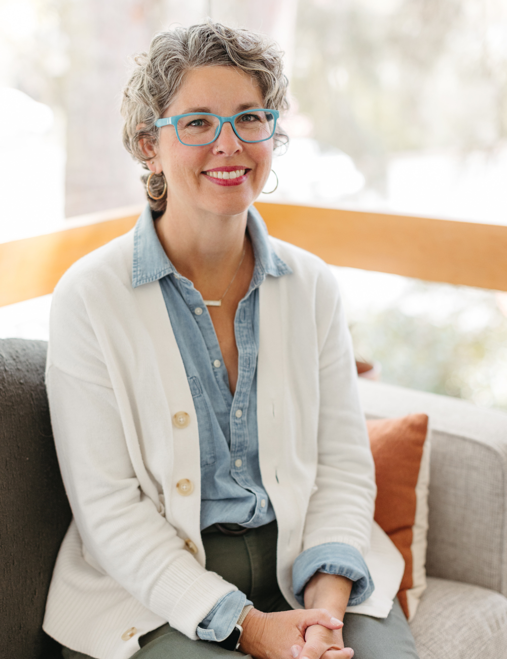 Therapist Kathleen sitting on a couch smiling.