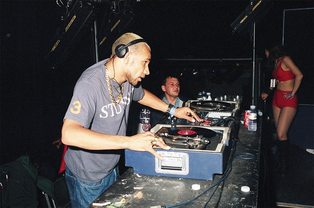 DJ Goldie performing at London rave event with turntables and club lighting