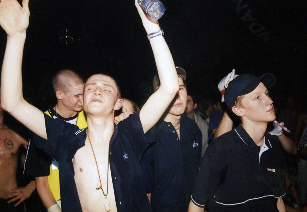 Crowd scene from UK underground rave with dancers raising their arms