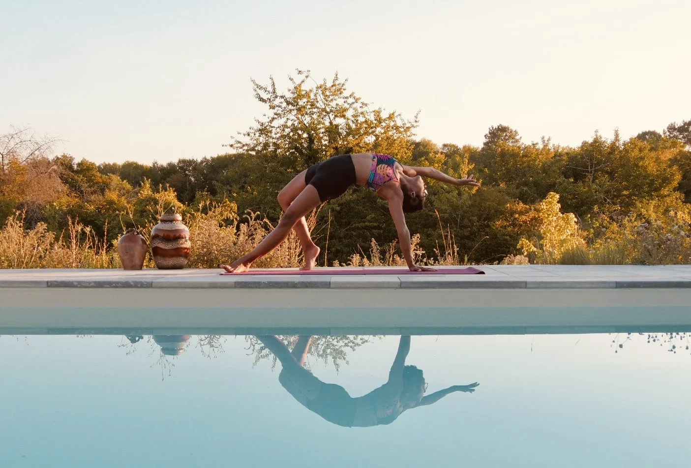 Groupe de personnes participant à un cours de yoga dans une salle avec miroir au mur et grandes fenêtres.