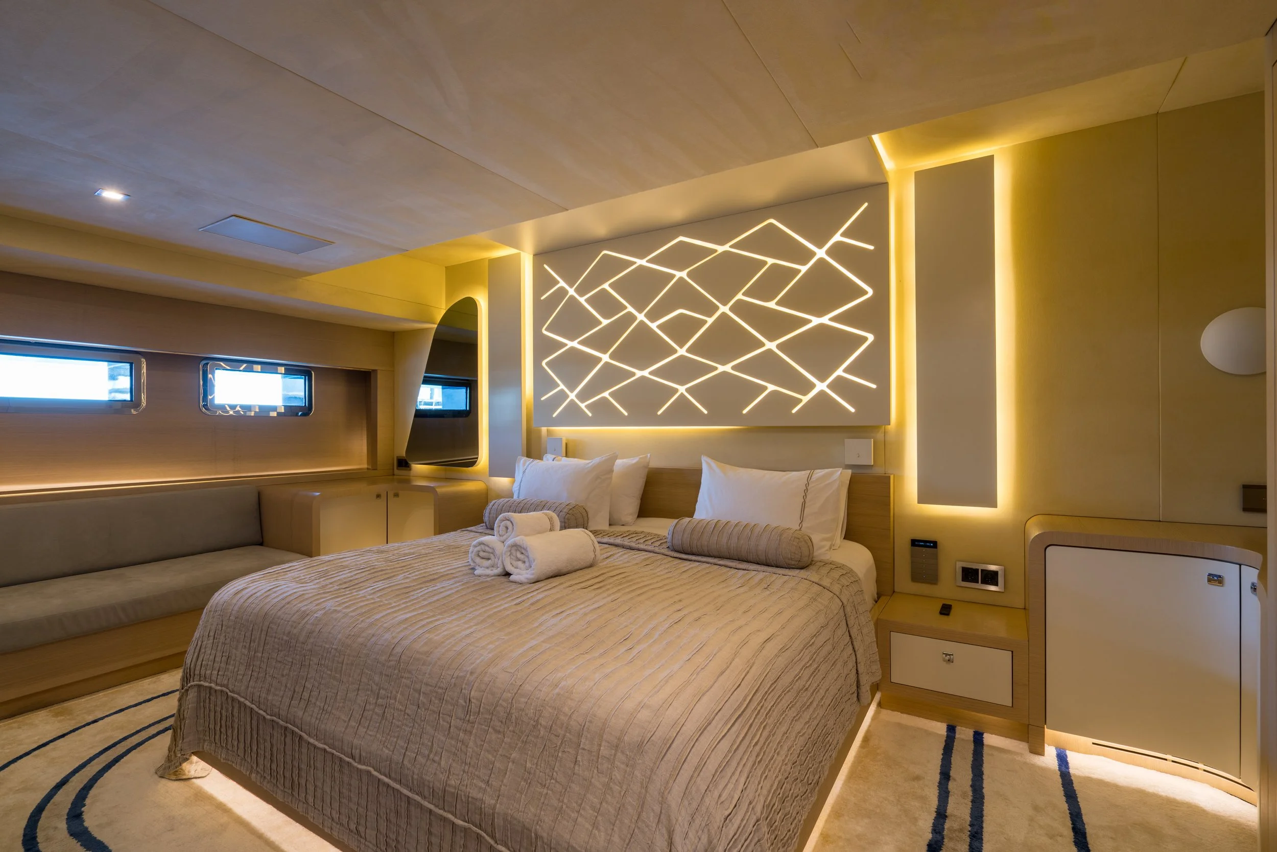 A modern hotel room with a bed, decorative lighting, and beige and cream-colored decor.