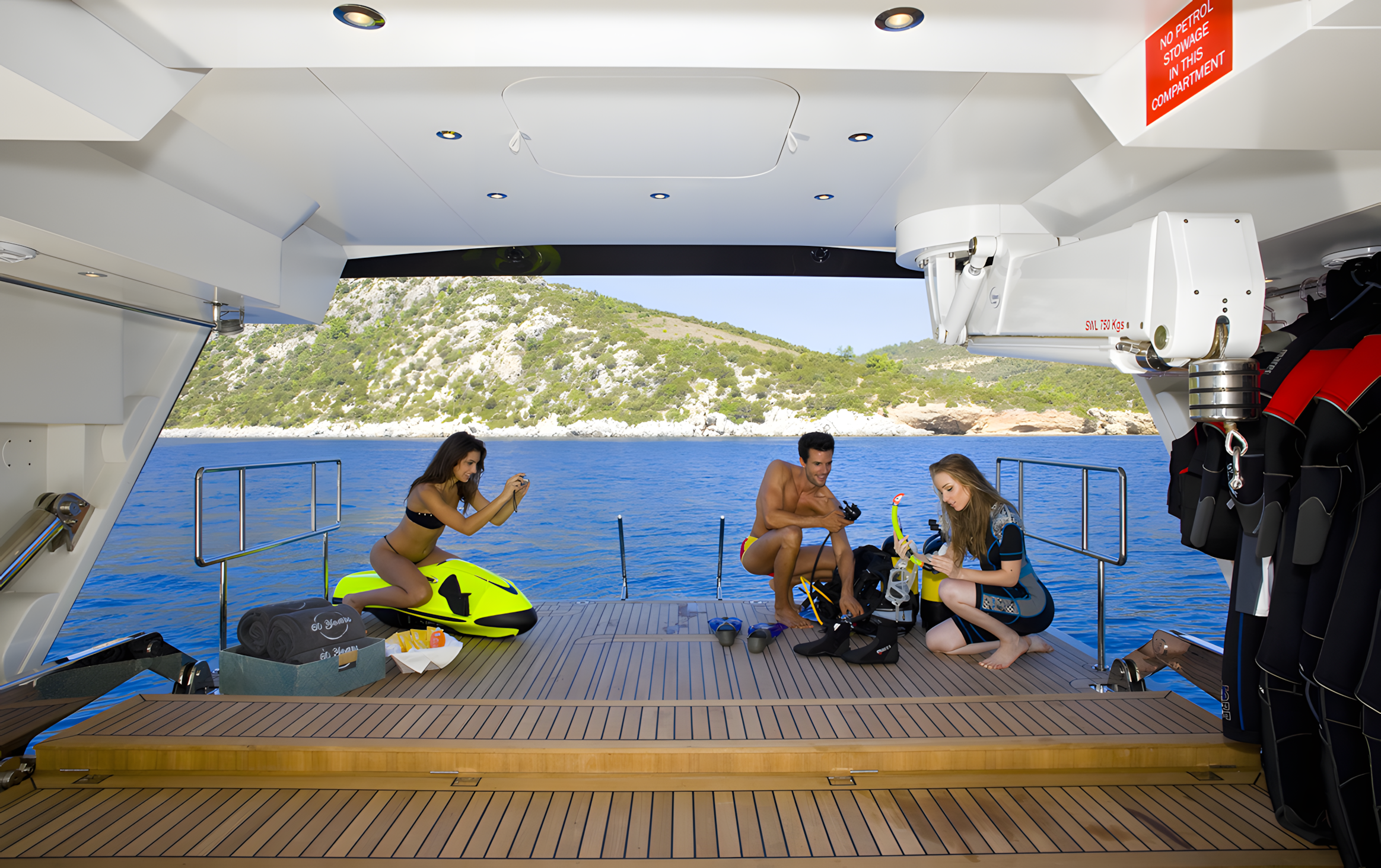 People on a yacht preparing for water activities, with a scenic view of hillside and water.