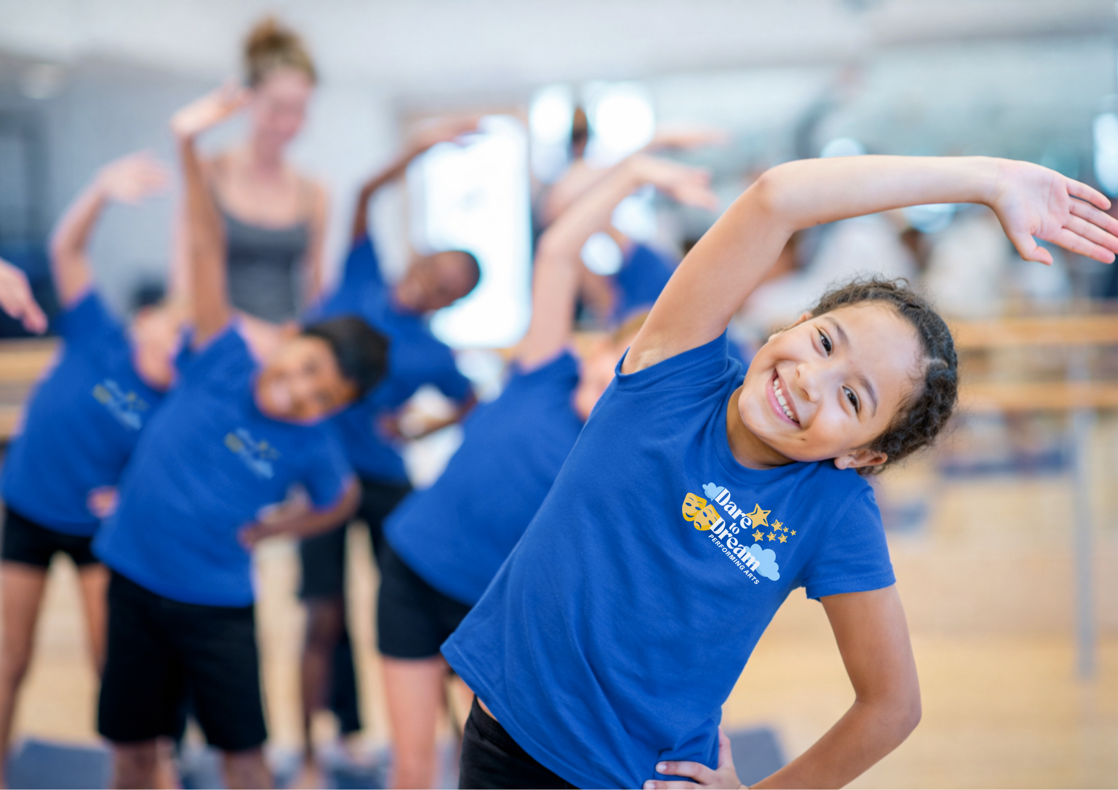 Dance class with young girl in focus smiling in blue dare to dream performing arts tshirt