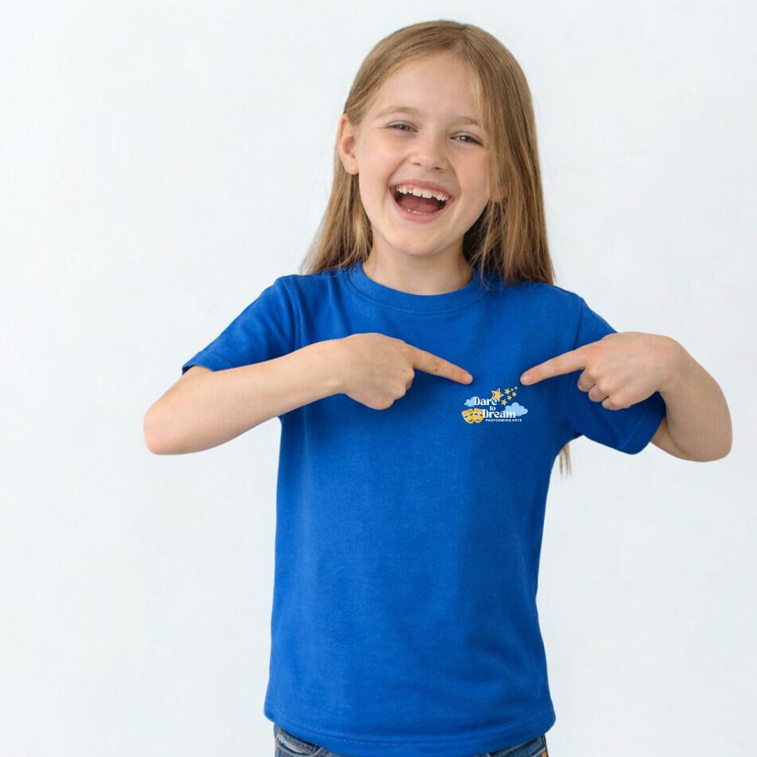 Young girl smiling and pointing to logo in blue dare to dream performing arts tshirt