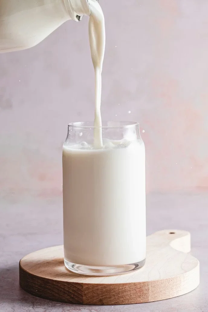 Freeze frame of milk being poured onto a glass cup, creating a slight splatter.