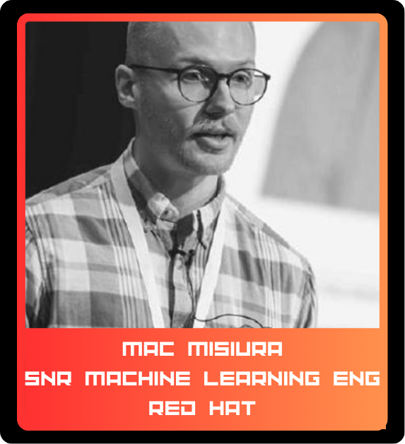 A man with glasses and a checkered shirt speaking, with a red hat and a name tag that reads 'Mac Misura, SNR Machine Learning Eng, Red Hat'.
