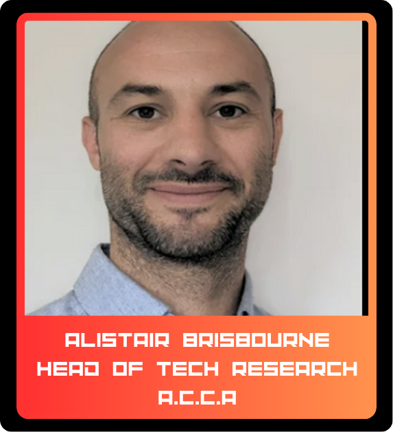 Photograph of a man with a light complexion, short dark hair, and a beard, wearing a light blue collared shirt, smiling at the camera. The background is plain white. The card's border is black and orange with a red bottom section containing white pix