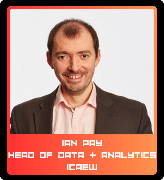 A professional headshot of a man with short brown hair and a beard, wearing a dark blazer over a light pink shirt, smiling at the camera.