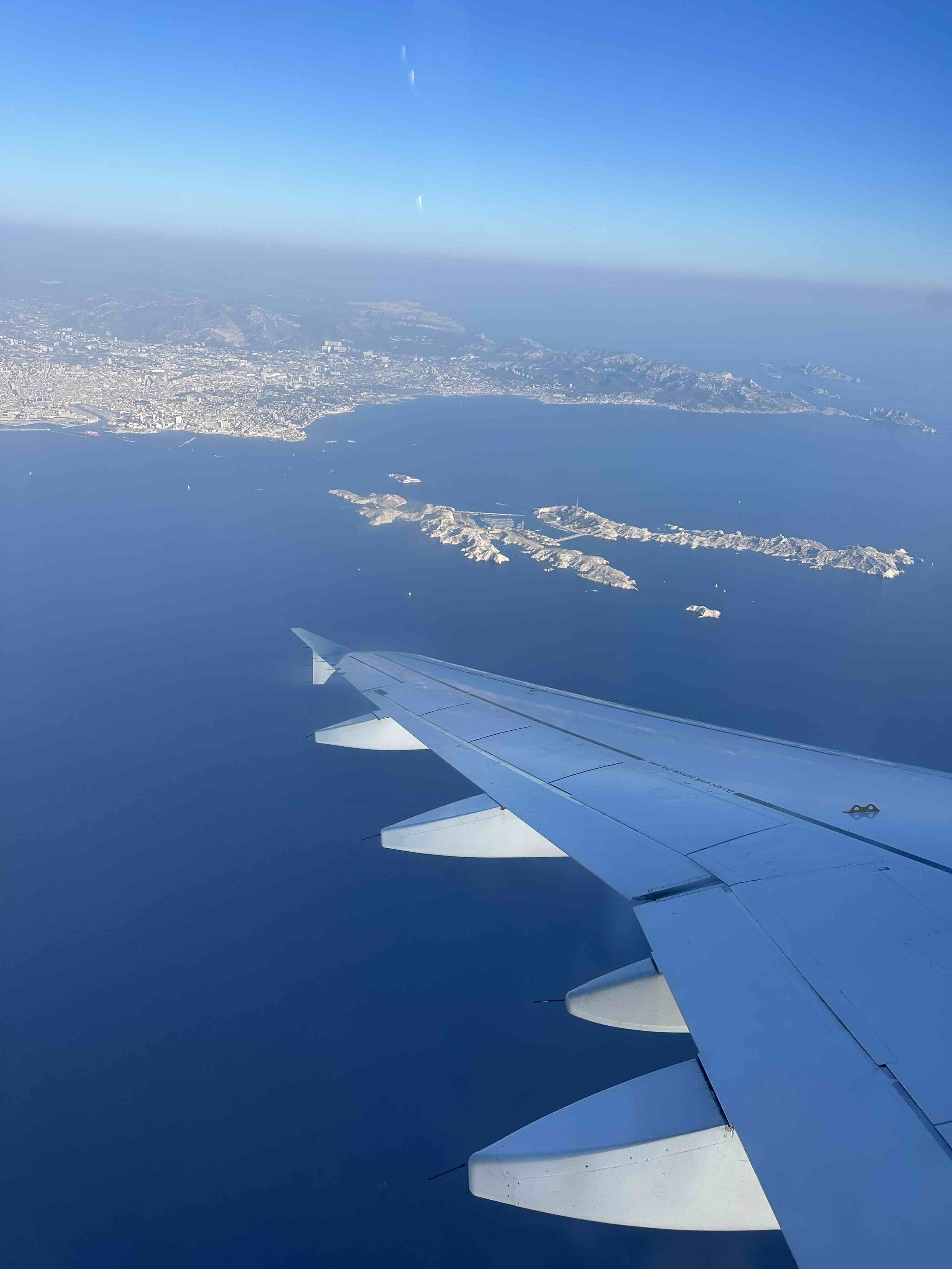 Aerial view of the coastline with islands and mountains as seen from the airplane window.