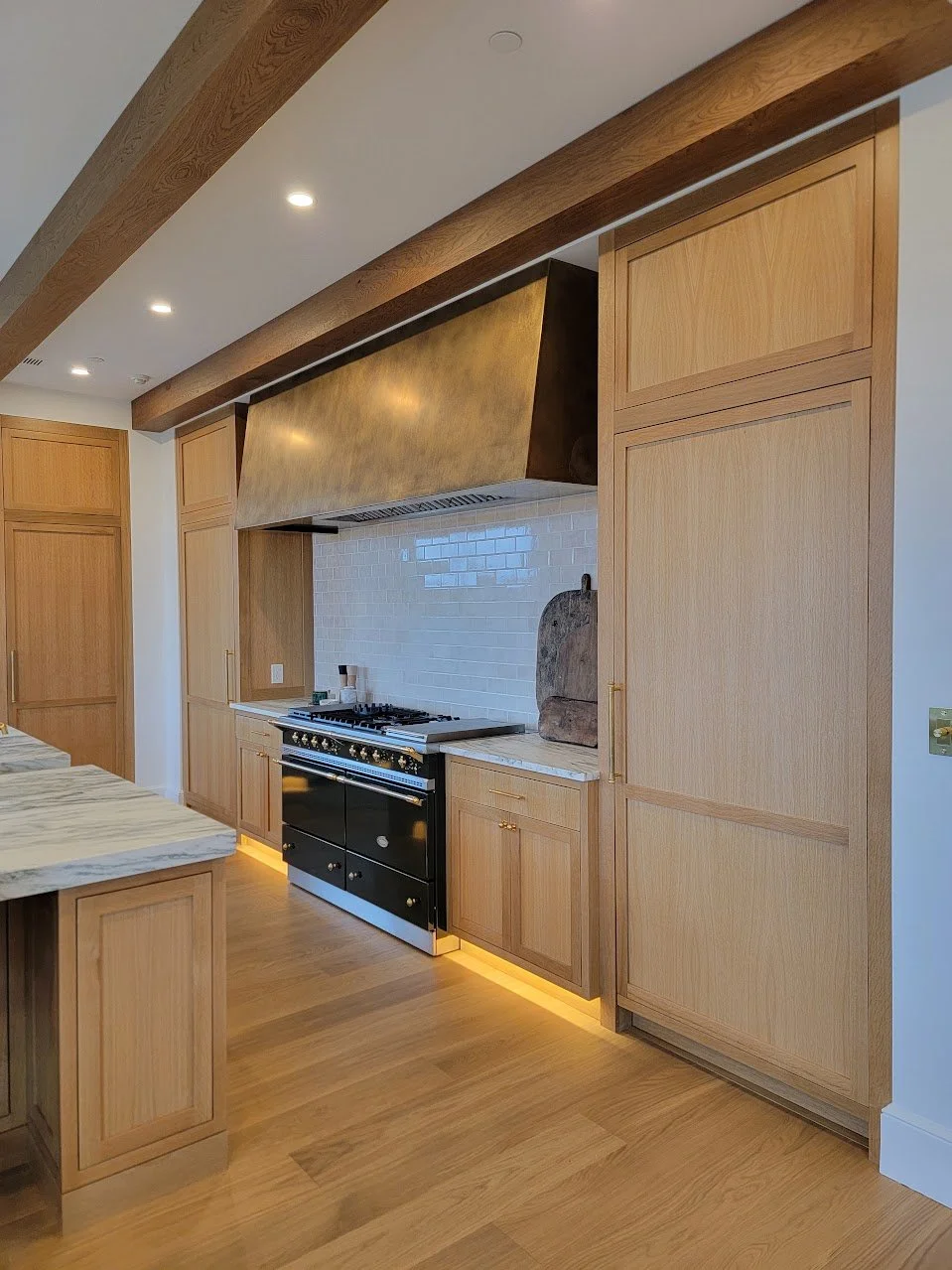 Range wall framed by integrated cabinetry and warm wood tones, creating a strong focal point within the kitchen.