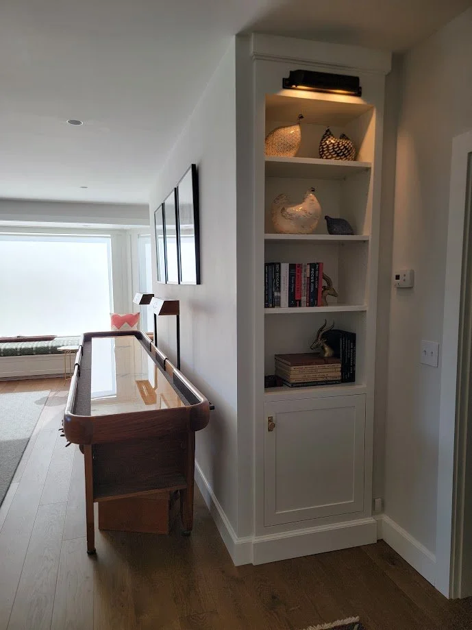 Custom built-in bookcase with integrated art lighting, blending display functionality with architectural millwork.