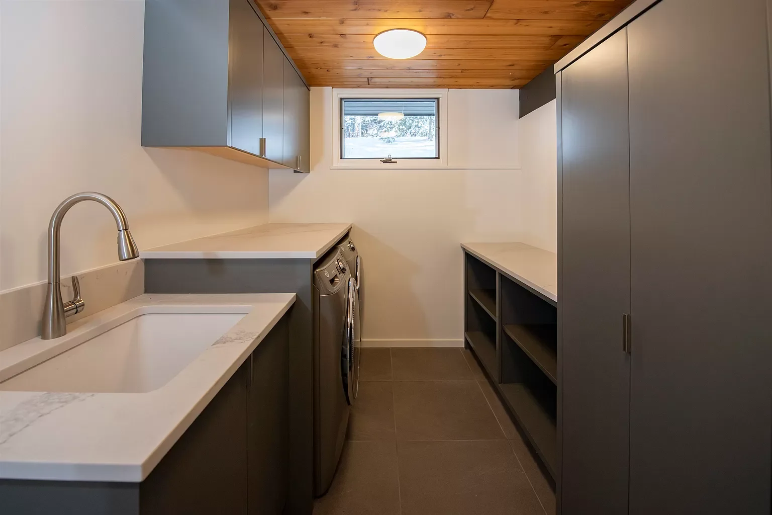 Laundry room with grey cabinets, a white countertop, a built-in sink, a small window, and a wood-paneled ceiling.