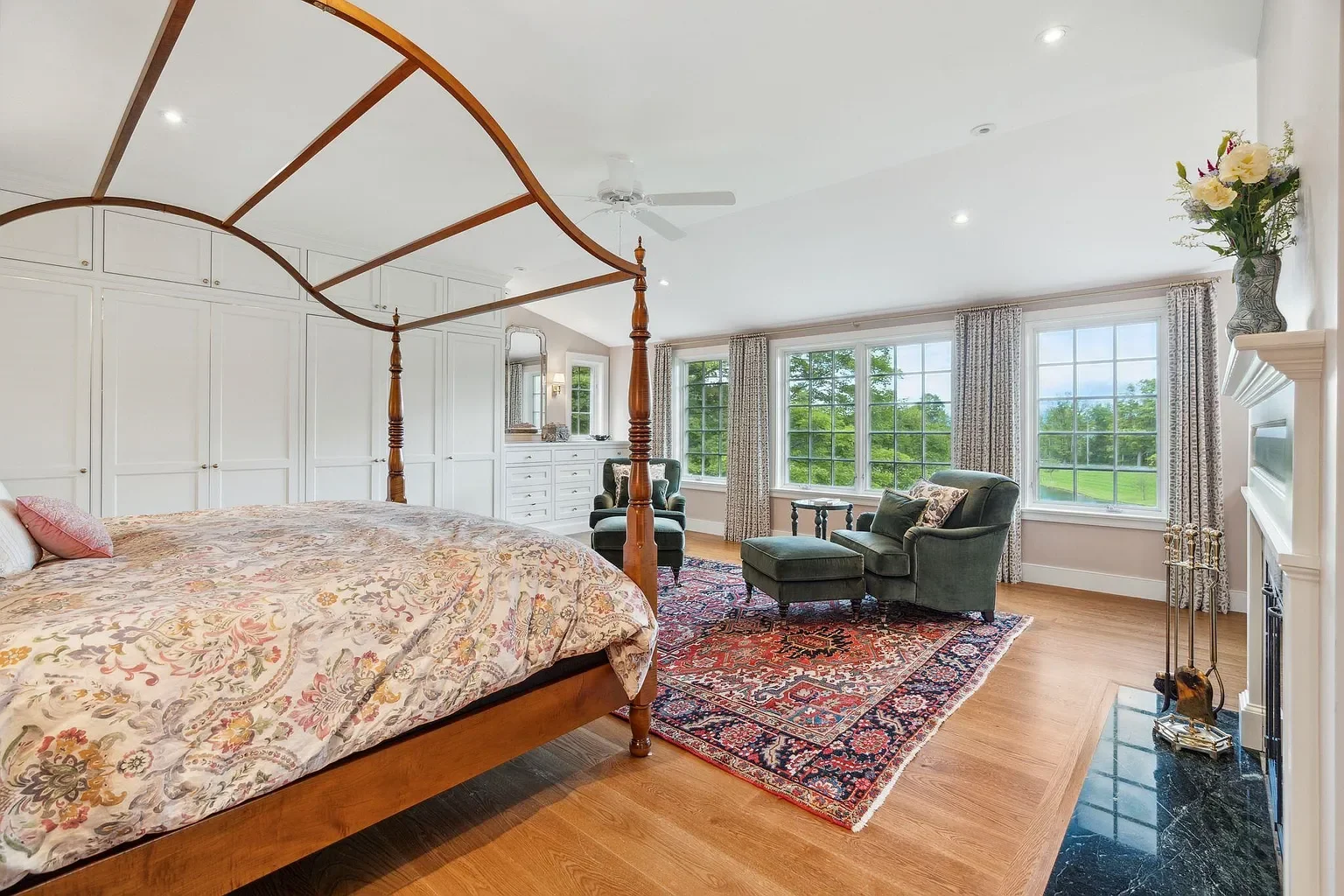 Bedroom with large windows, green armchair, patterned rug, and white built-in closet.