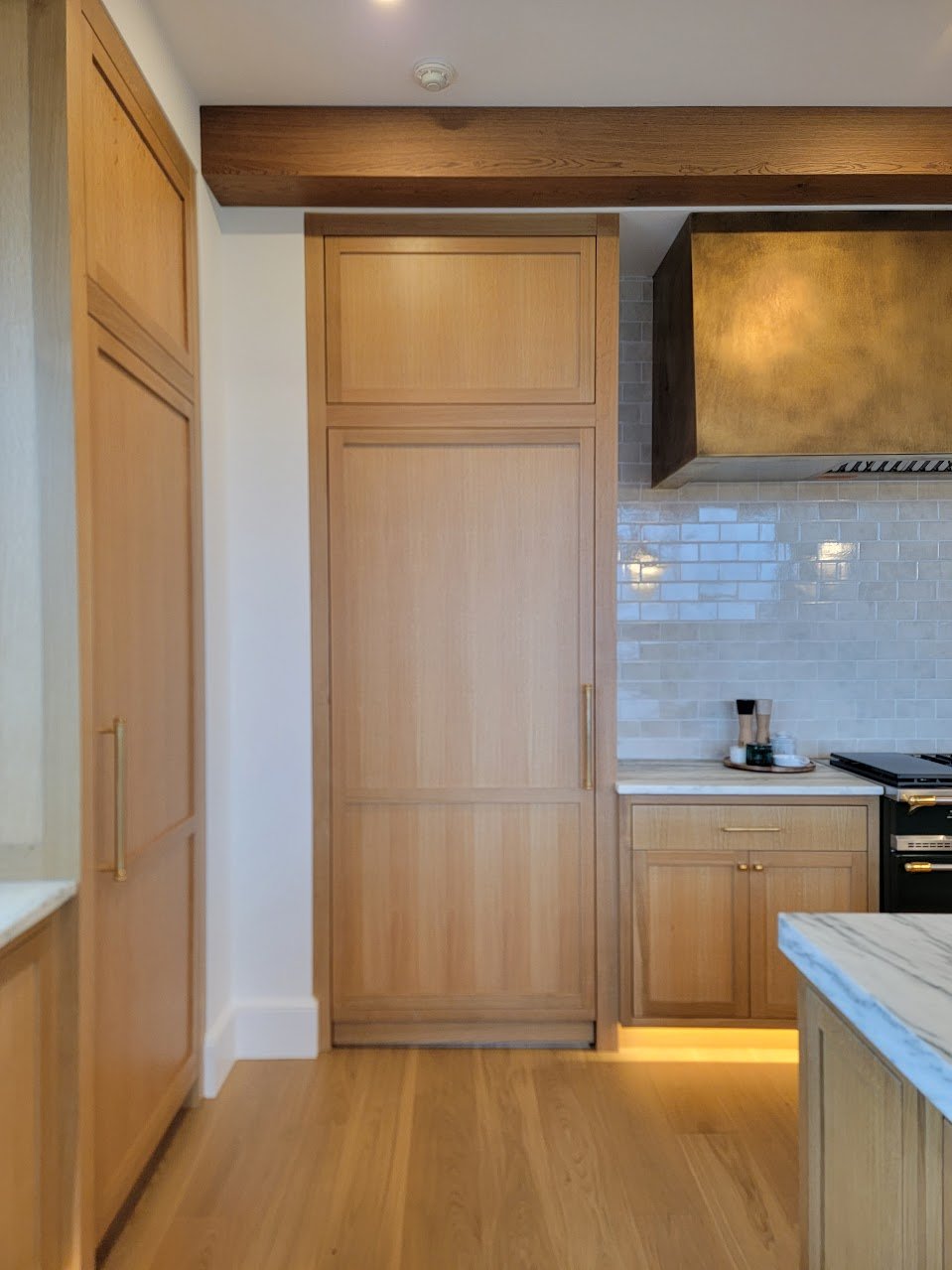 Concealed walk-in pantry door integrated into the quartersawn white oak cabinetry to preserve clean elevations and uninterrupted sightlines.