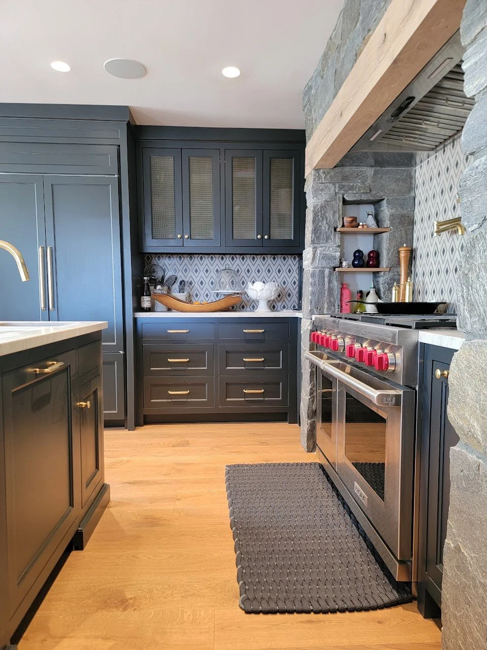 Custom charcoal kitchen featuring paneled refrigerator, stone countertops, and tailored millwork detailing.
