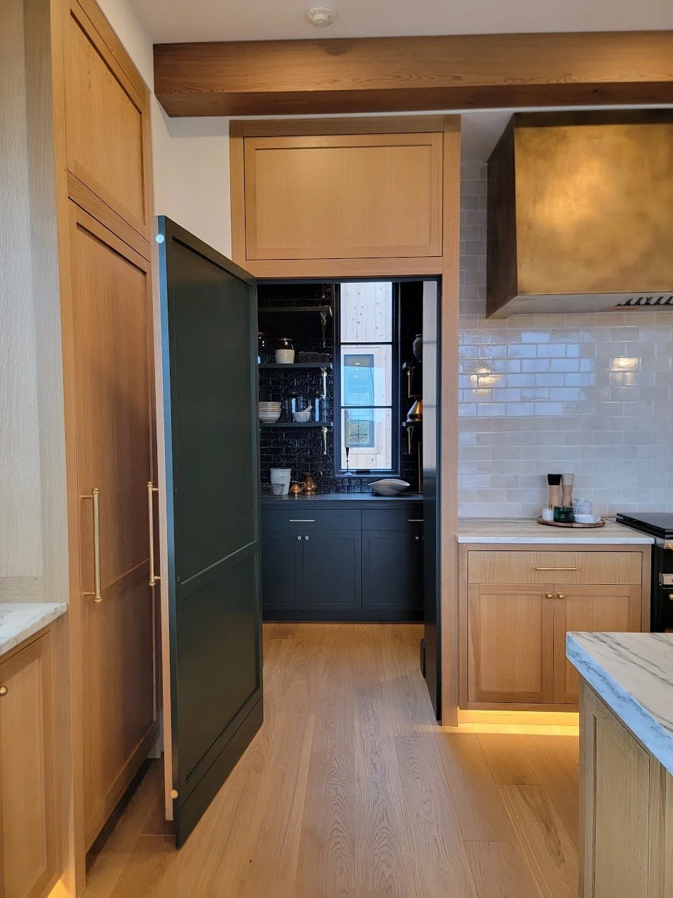 Hidden pantry door revealed, providing access to a walk-in pantry while maintaining the kitchen’s architectural continuity.