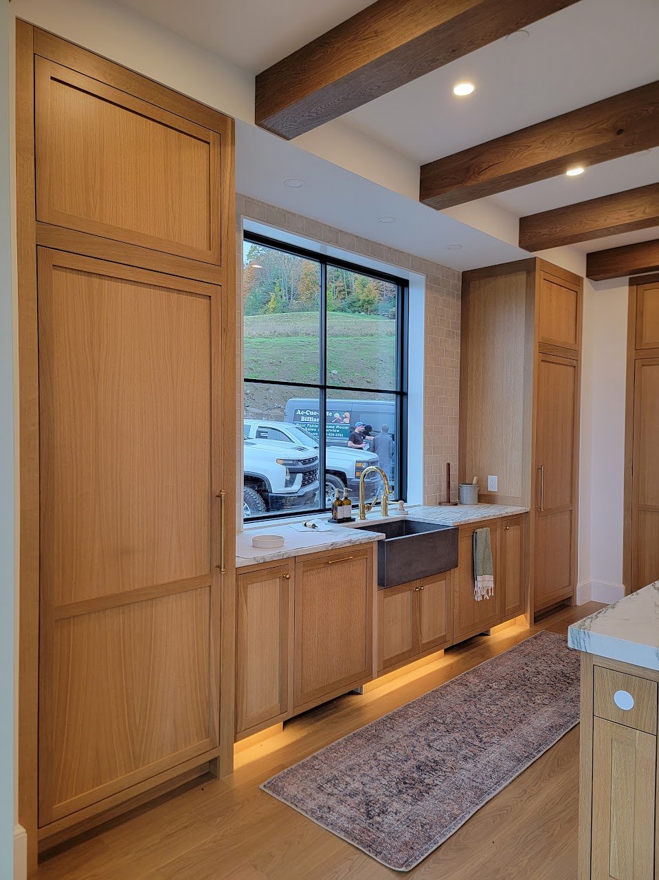 Sink wall detailed with farmhouse sinks and integrated cabinetry, balancing everyday function with architectural restraint.