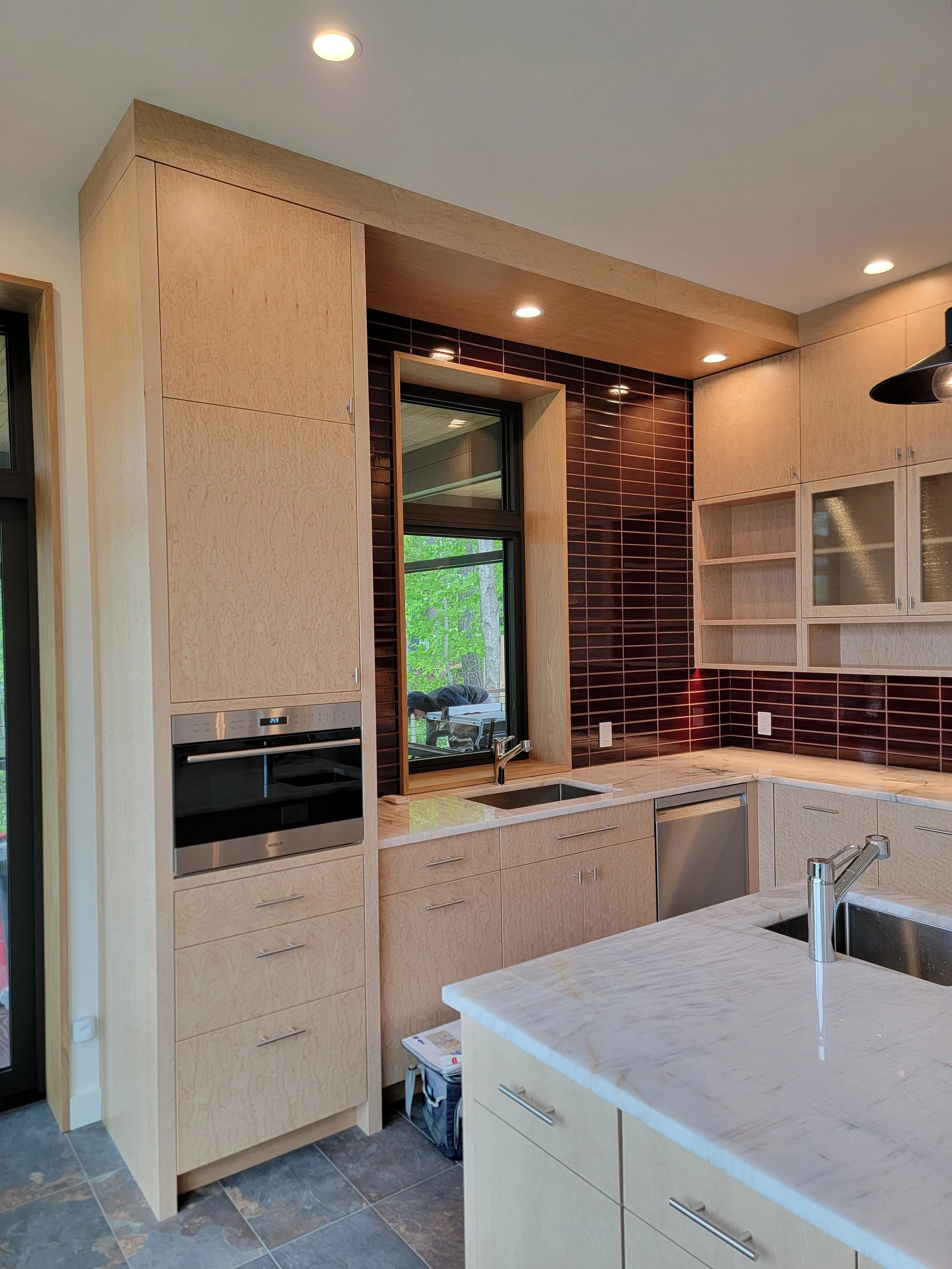 Close-up of custom birdseye maple kitchen cabinetry showcasing the distinctive grain pattern and precision modern joinery. The cabinetry’s simple geometry allows the natural beauty of the maple to take center stage.