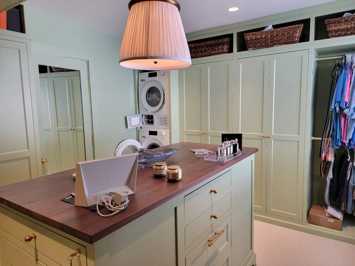 Bold green custom dressing room with center island, built-in cabinetry, and tailored storage solutions.