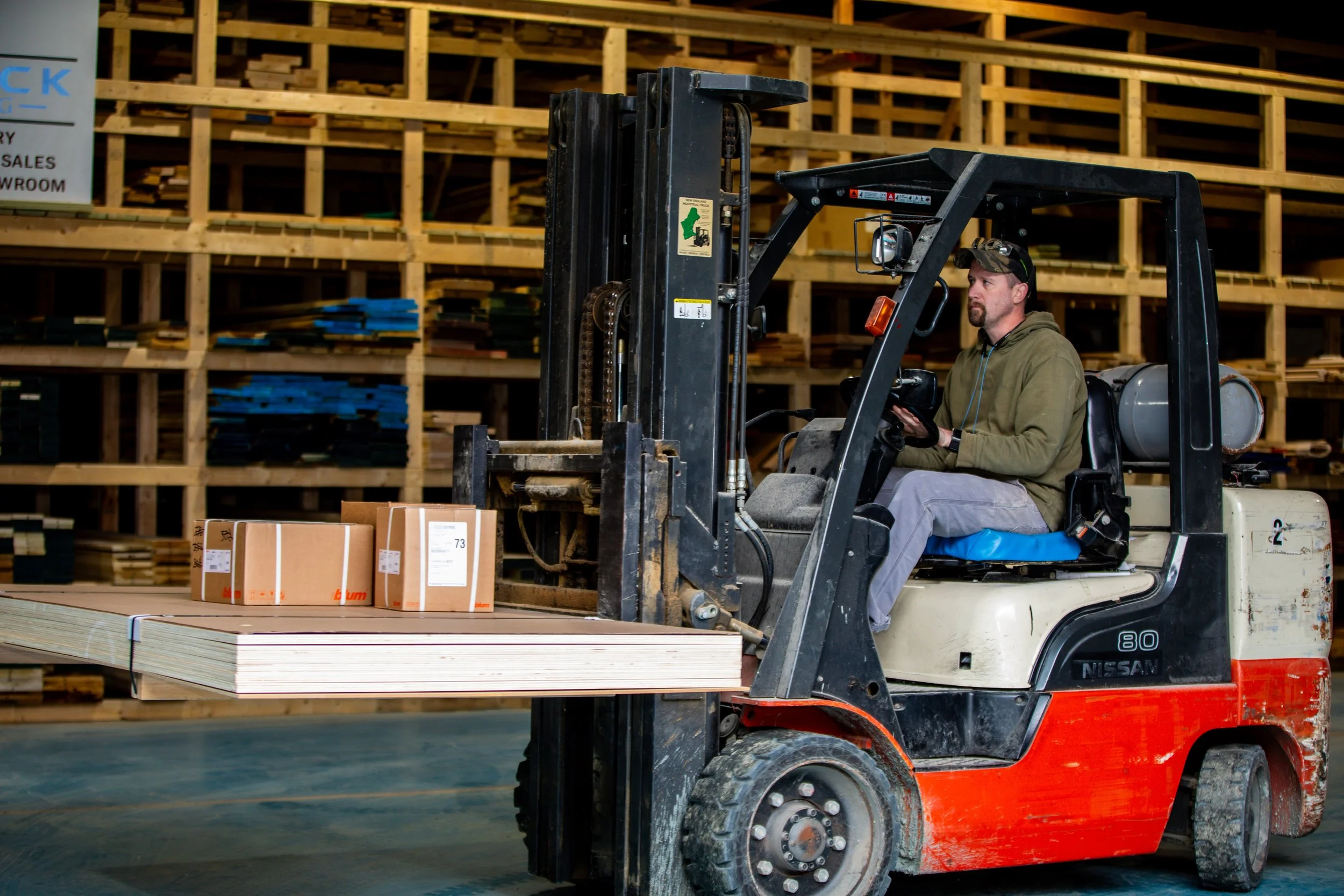 Forklift operator handling hardwood lumber inventory at a lumber yard